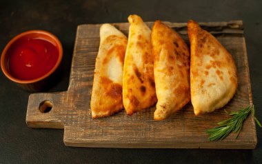 Ahşap doğrama tahtası üzerinde domates soslu Geleneksel Latin Amerika kızarmış empanadas 