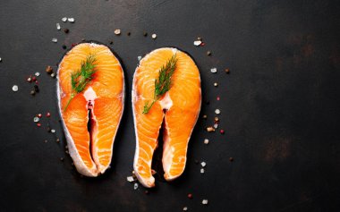 Siyah taş arka plan üzerinde baharat ve dereotu ile taze çiğ somon biftek