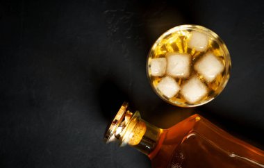 Siyah arka planda buz küpleri ve viski şişesi ile viski Bir bardak 