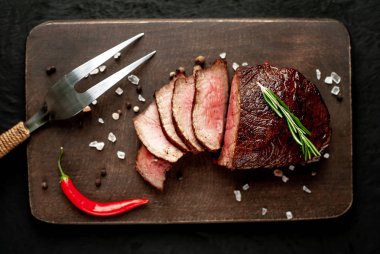 Siyah taş arka plan üzerinde baharat ve biberiye dal ile Taze ızgara biftek