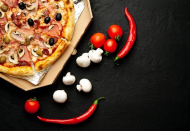 Siyah taş arka plan üzerinde mantar, domates, zeytin ve jambon ile taze ev yapımı pizza
