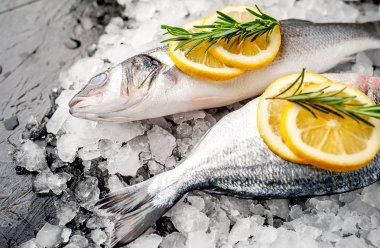 Soğuk ezilmiş buz yığını üzerinde limon dilimleri ve biberiye ile taze balık yakın görünümü