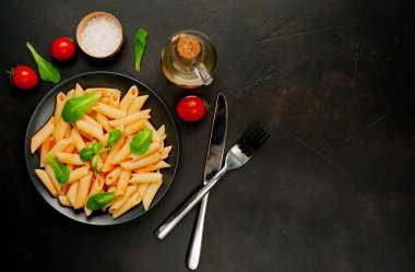 domates soslu makarna, yeşil yapraklar ve taş siyah arka plan üzerinde olgun domates