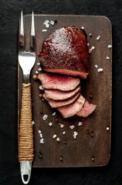 Ahşap doğrama tahtası üzerinde et çatal ile dilimlenmiş biftek üst görünümü  