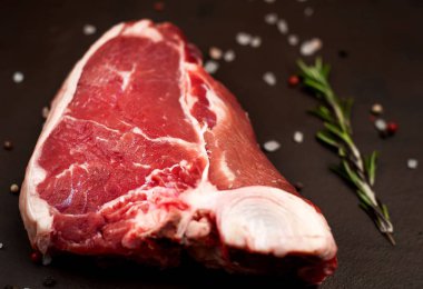 Taş arka planda baharat ve biberiye dal ile Çiğ yağ biftek