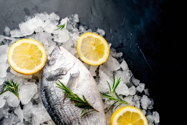 Soğuk ezilmiş buz yığını üzerinde limon dilimleri ve biberiye ile taze balık yakın görünümü