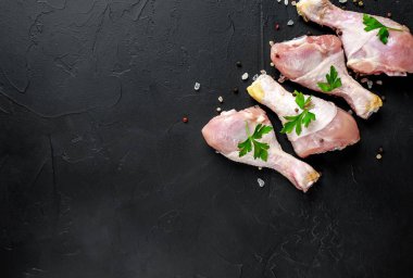 Baharat, tuz ve maydanoz siyah taş arka plan üzerinde yaprakları ile Tavuk bacakları