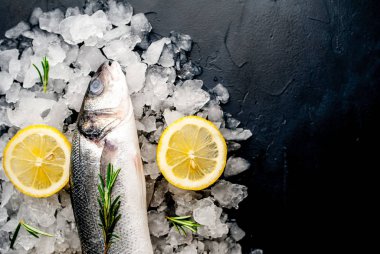 Soğuk ezilmiş buz yığını üzerinde limon dilimleri ve biberiye ile taze balık yakın görünümü