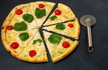 siyah taş arka plan üzerinde kiraz domates ve taze ıspanak yaprakları ile pizza