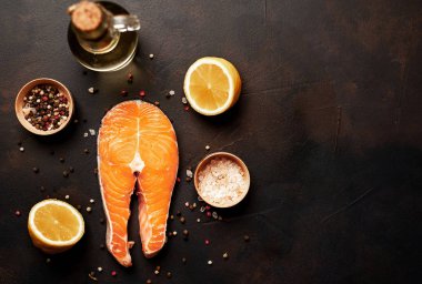 Siyah taş arka plan üzerinde baharat ve limon ile taze çiğ somon biftek