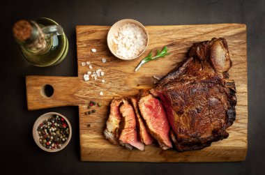 Siyah taş arka plan üzerinde ahşap doğrama tahtası üzerinde baharat ile Yağlı ızgara domuz biftek
