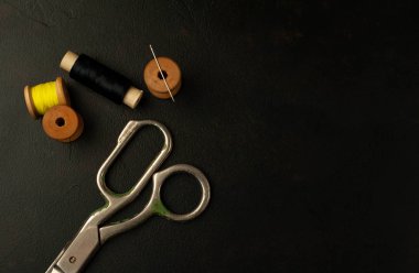 siyah arka plan üzerinde dikiş makaraları yığını ile terzi makasları 