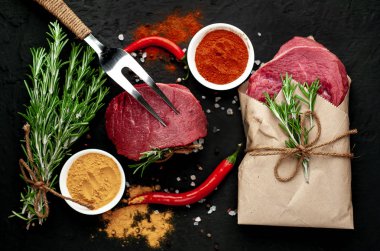 Siyah taş arka planda renkli baharatlar ile Çiğ biftek