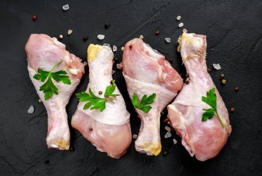 Baharat, tuz ve maydanoz siyah taş arka plan üzerinde yaprakları ile Tavuk bacakları