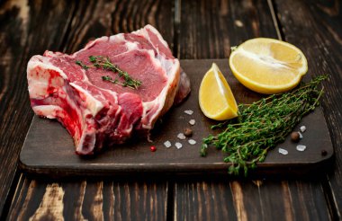 Ahşap arka plan üzerinde biberiye ve limon dilimleri ile Çiğ yağ domuz biftek 