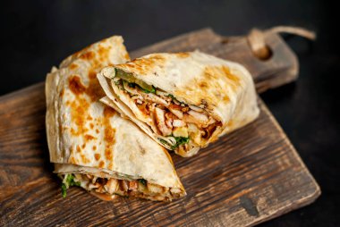 Ahşap doğrama tahtası üzerinde tavuk ve sebze ile sarılmış ev yapımı Meksika burrito 
