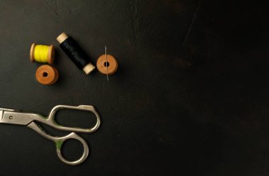 siyah arka plan üzerinde dikiş makaraları yığını ile terzi makasları 