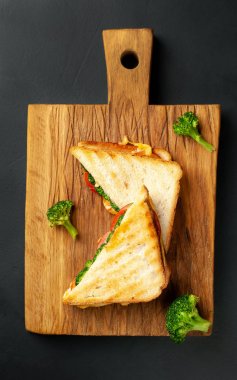 Ahşap doğrama tahtasında jambon, taze brokoli ve peynirile taze ızgara sandviçler