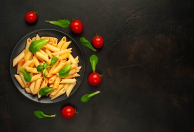 domates soslu makarna, yeşil yapraklar ve taş siyah arka plan üzerinde olgun domates