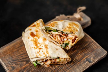 Ahşap doğrama tahtası üzerinde tavuk ve sebze ile sarılmış ev yapımı Meksika burrito 