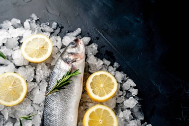 Soğuk ezilmiş buz yığını üzerinde limon dilimleri ve biberiye ile taze balık yakın görünümü