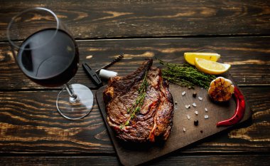 Taze kavrulmuş biftek ahşap doğrama tahtası üzerinde limon dilimleri ve ızgara sarımsak ile servis