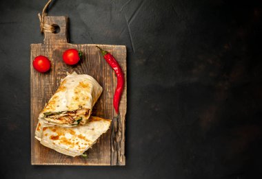 Geleneksel Meksika burrito tavuk ve sebze ile sarılmış ahşap doğrama tahtası üzerinde olgun domates ile servis 
