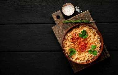 koyu taş arka plan üzerinde domates sosu ve maydanoz yaprakları ile İtalyan spagetti makarna