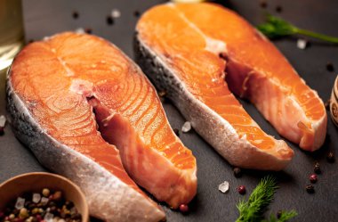 Siyah taş arka plan üzerinde baharat ve dereotu ile taze çiğ somon biftek