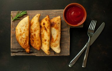 Ahşap doğrama tahtası üzerinde domates soslu Geleneksel Latin Amerika kızarmış empanadas 