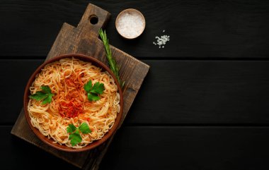 koyu taş arka plan üzerinde domates sosu ve maydanoz yaprakları ile İtalyan spagetti makarna
