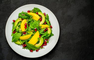 Arugula, ıspanak, dilimlenmiş mango ve avokado, nar ve ayçiçeği tohumu ile taze vegan salata