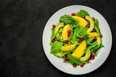 Arugula, ıspanak, dilimlenmiş mango ve avokado, nar ve ayçiçeği tohumu ile taze vegan salata