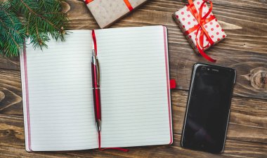 Eski ahşap arka plan üzerinde kırmızı yay ve boş defter ile hediye kutuları yığını 