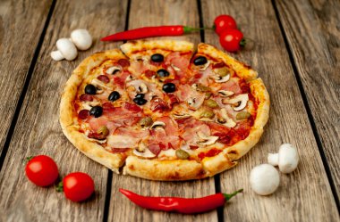 Ahşap arka plan üzerinde mantar, domates, zeytin ve jambon ile taze ev yapımı pizza