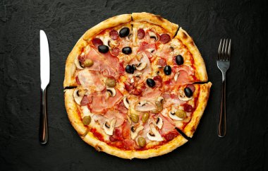 Siyah taş arka plan üzerinde mantar, domates, zeytin ve jambon ile taze ev yapımı pizza