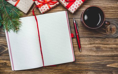 Eski ahşap arka plan üzerinde kırmızı yay ve boş defter ile hediye kutuları yığını 