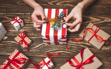 Eski ahşap arka plan üzerinde kırmızı yay ile kadın elleri dekorasyon hediye kutuları 