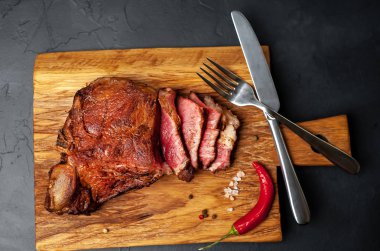 Siyah taş arka plan üzerinde doğrama tahtası üzerinde baharat ve biber ile Yağlı ızgara domuz biftek
