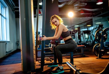 Genç sporcu kadın boş spor salonunda kas çalıştırıyor.  