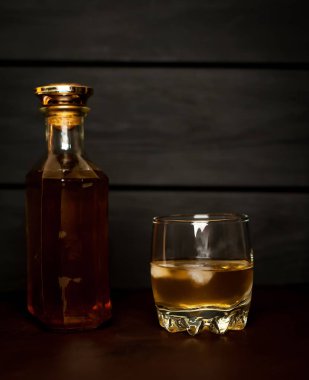 Siyah arka planda buz küpleri ve viski şişesi ile viski Bir bardak 