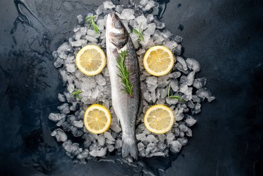 Soğuk ezilmiş buz yığını üzerinde limon dilimleri ve biberiye ile taze balık yakın görünümü