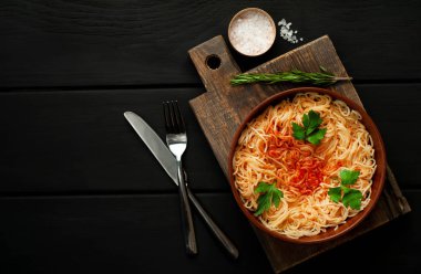 koyu taş arka plan üzerinde domates sosu ve maydanoz yaprakları ile İtalyan spagetti makarna