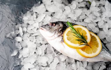 Soğuk ezilmiş buz yığını üzerinde limon dilimleri ve biberiye ile taze balık yakın görünümü