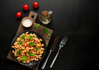 taş siyah arka plan üzerinde ahşap doğrama tahtası üzerinde domates soslu makarna