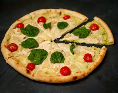siyah taş arka plan üzerinde kiraz domates ve taze ıspanak yaprakları ile pizza