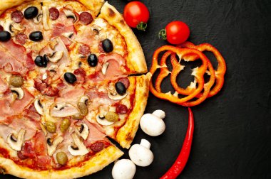 Siyah taş arka plan üzerinde mantar, domates, zeytin ve jambon ile taze ev yapımı pizza