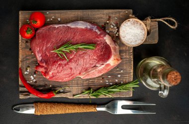 Ahşap doğrama tahtasında biberiye, domates ve biberiye ile taze çiğ biftek 