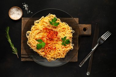 koyu taş arka plan üzerinde domates sosu ve maydanoz yaprakları ile İtalyan spagetti makarna