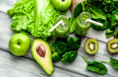 Gri arka planda sebze ve meyve ile Taze yeşil smoothie